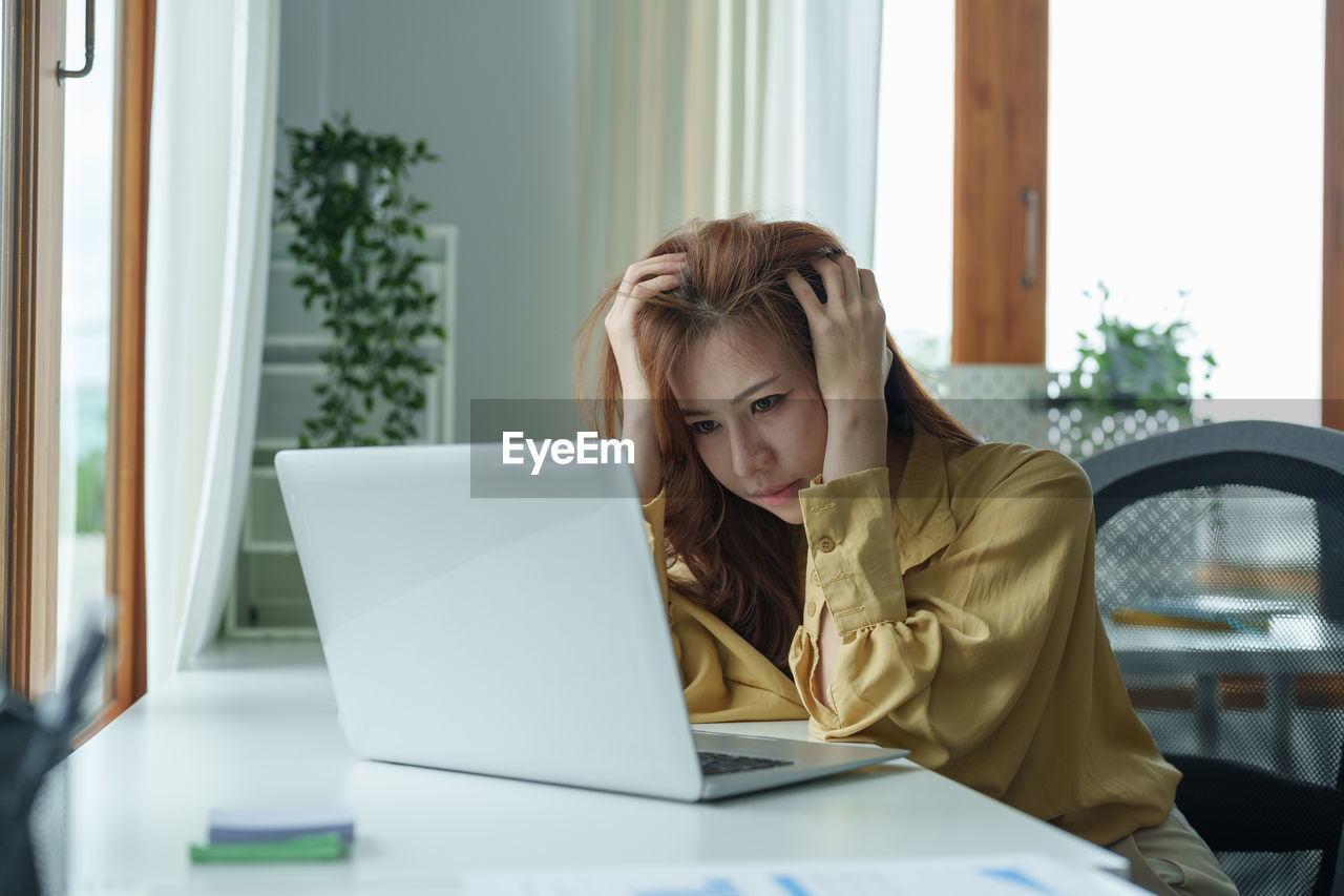 young woman using laptop while sitting at home