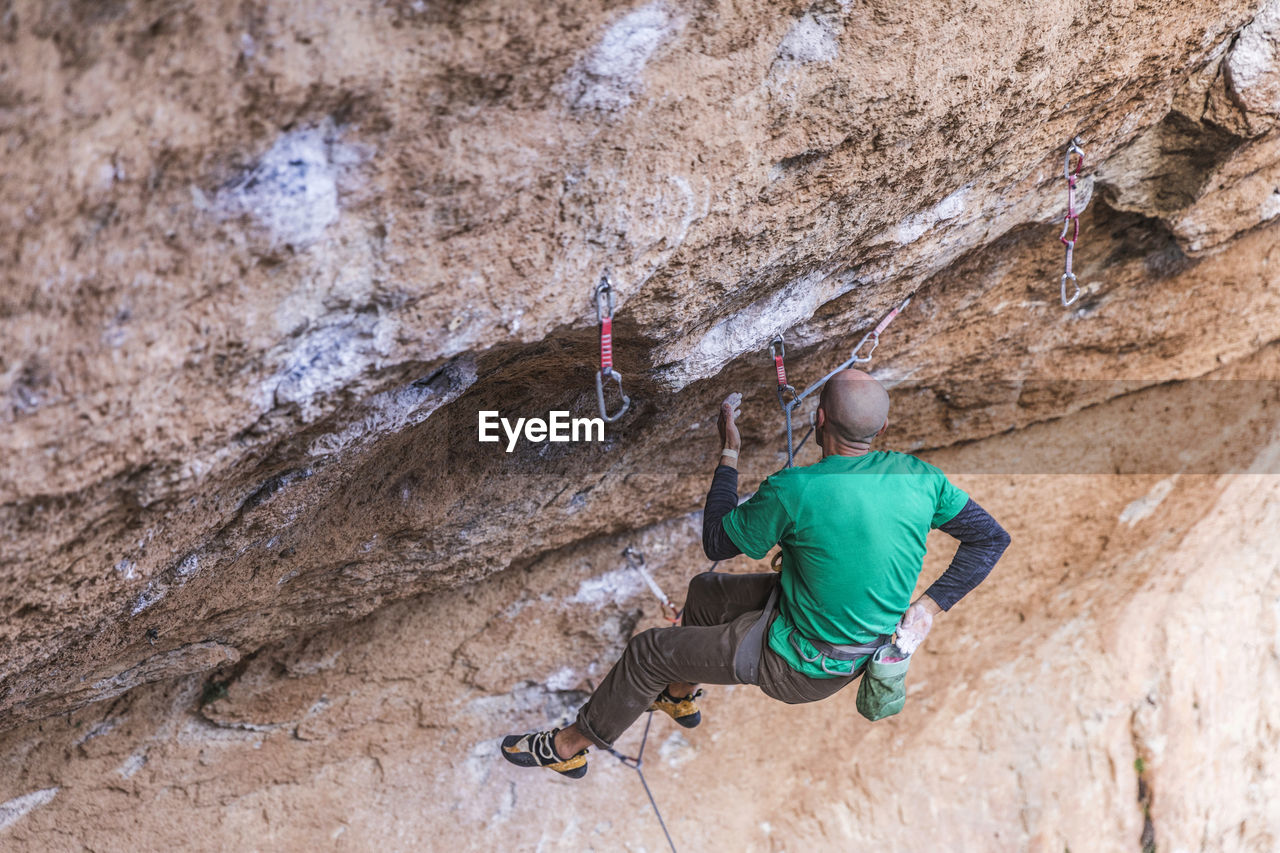 Climber hanging on rope on rough cliff