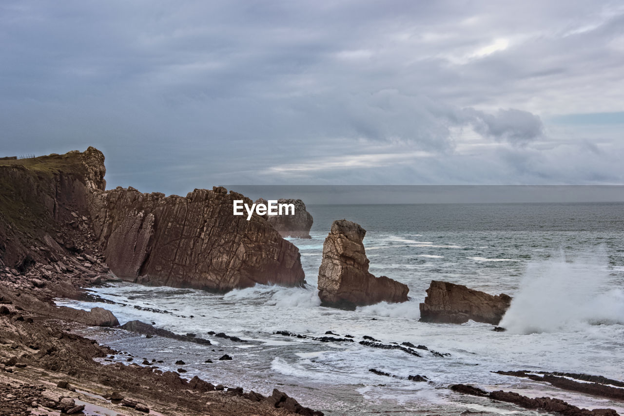 ROCKS ON SHORE AGAINST SKY