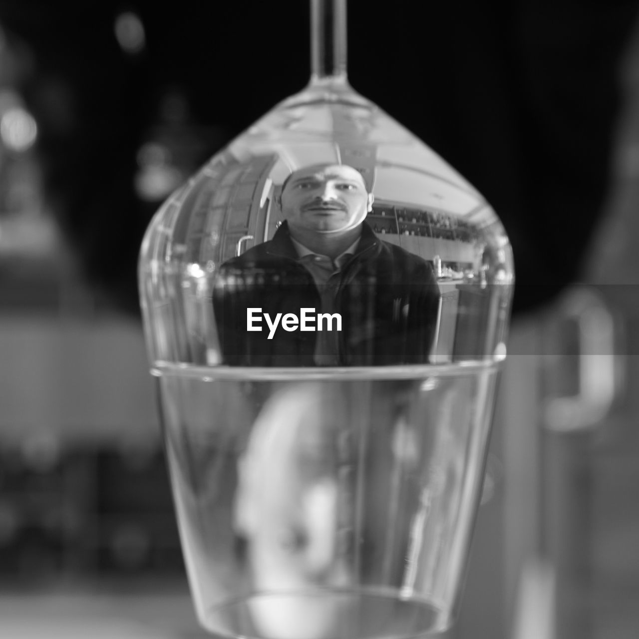 Reflection of man in upside down wineglass