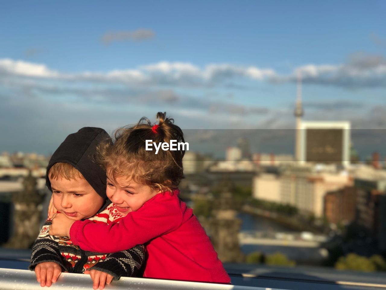 Cute siblings standing against cityscape