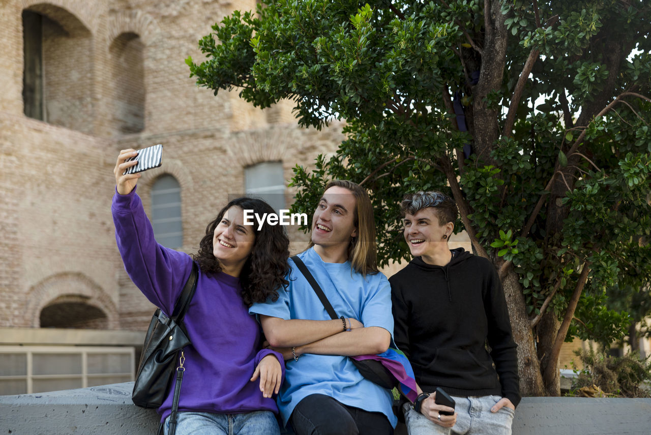 Young diverse friends taking selfie with a mobile phone outdoors.