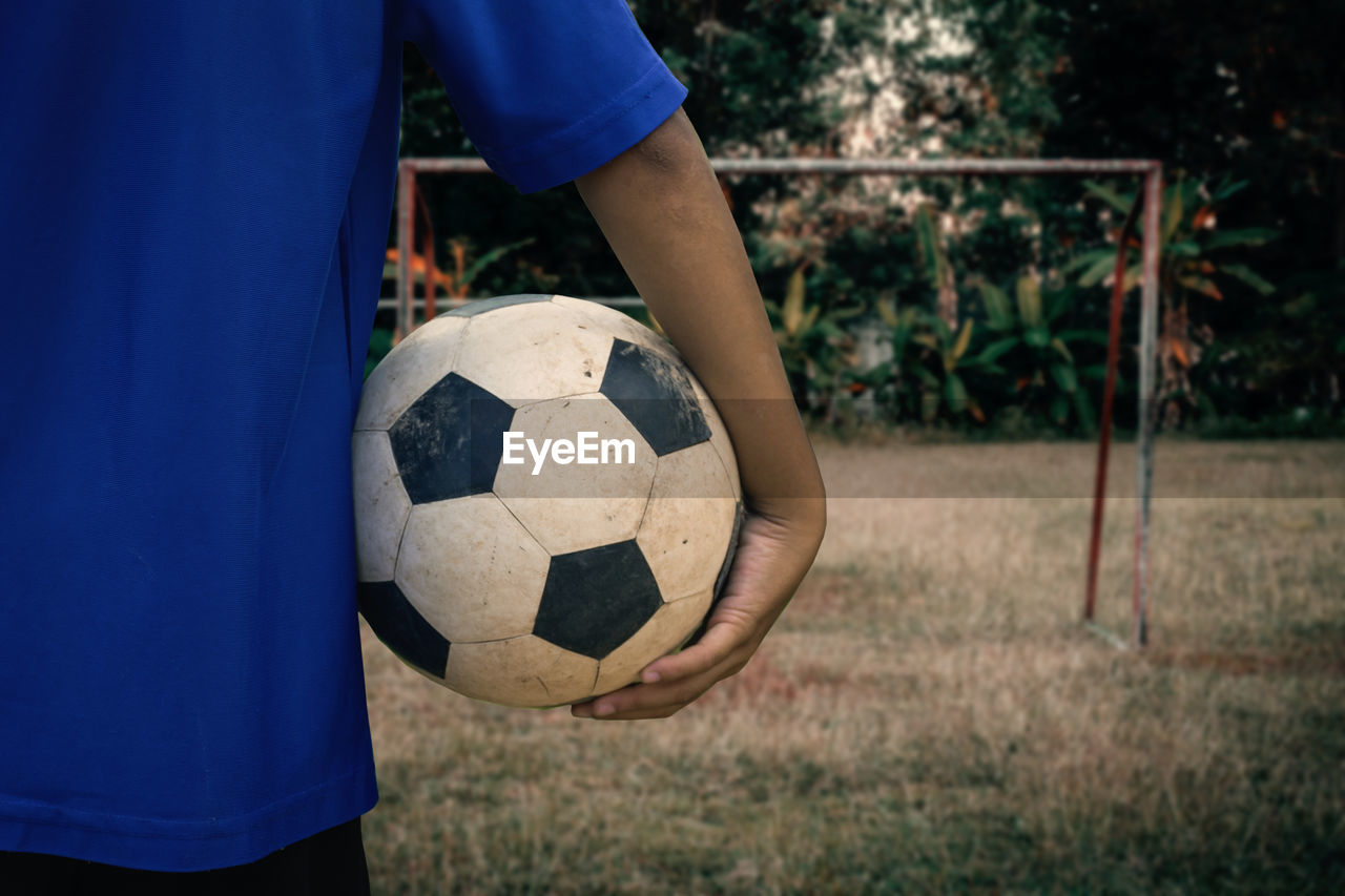 Midsection of man holding soccer ball