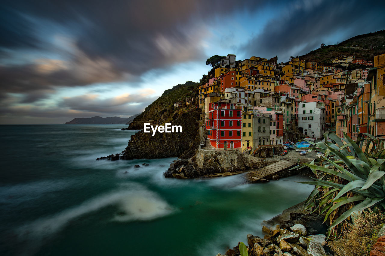 View of houses by sea against sky