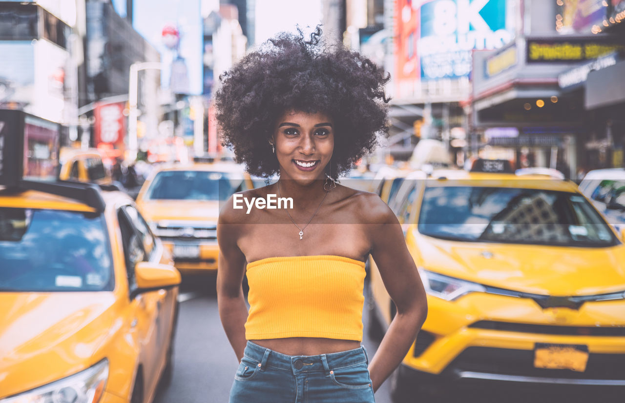 Portrait of confident young woman with afro hairstyle standing on city street