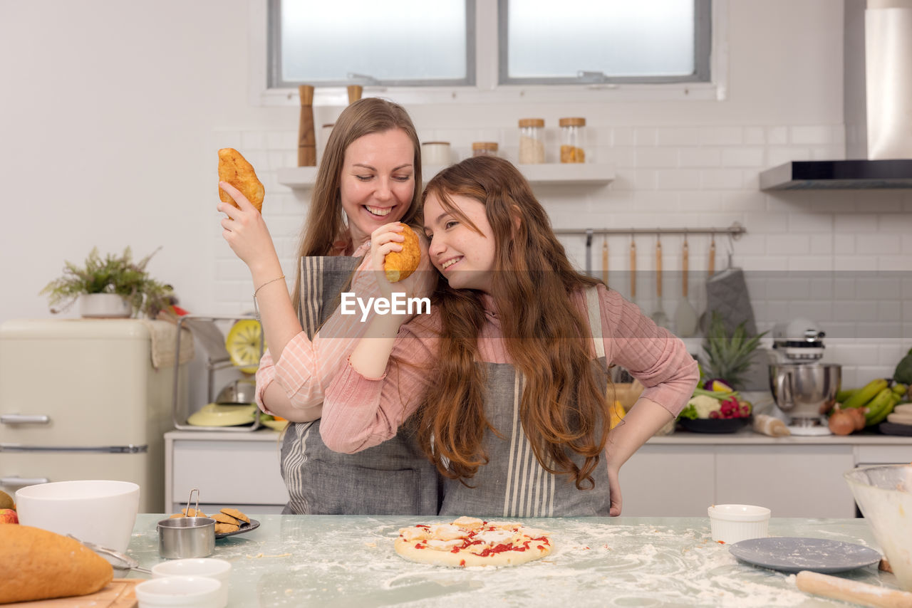 Mother and daughters use bread to sing and entertain one other.