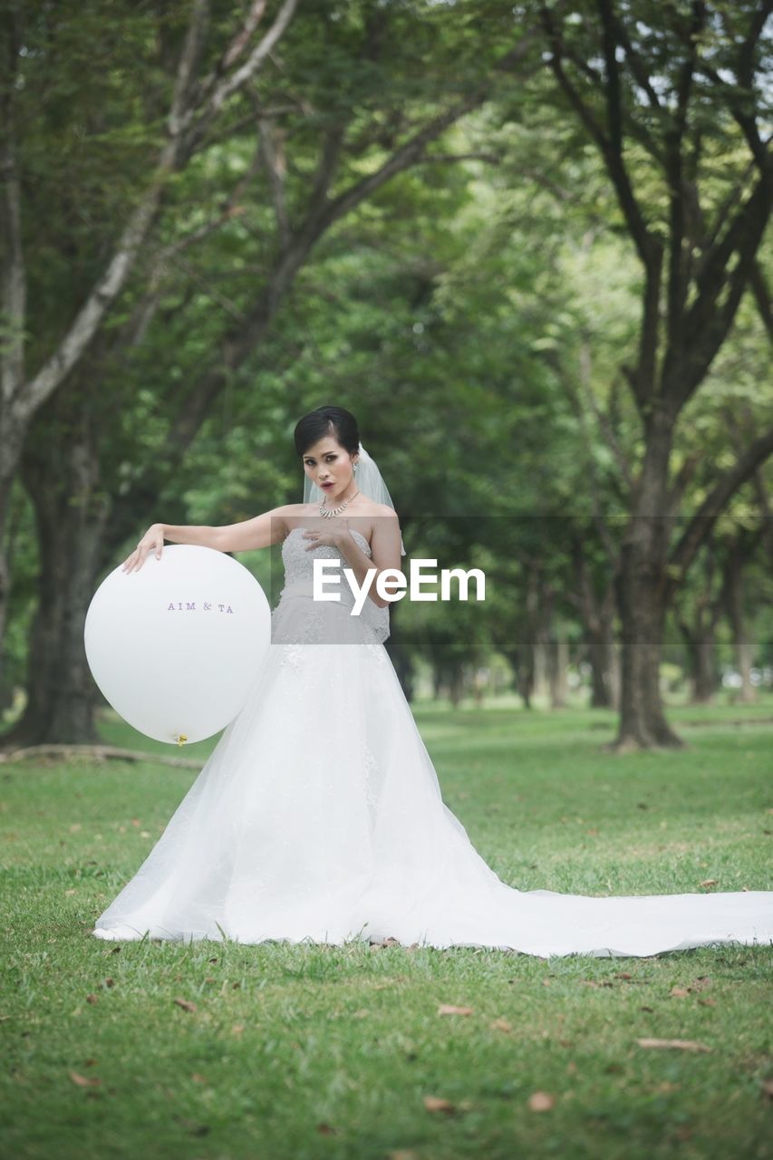 Portrait of bride holding balloon at park