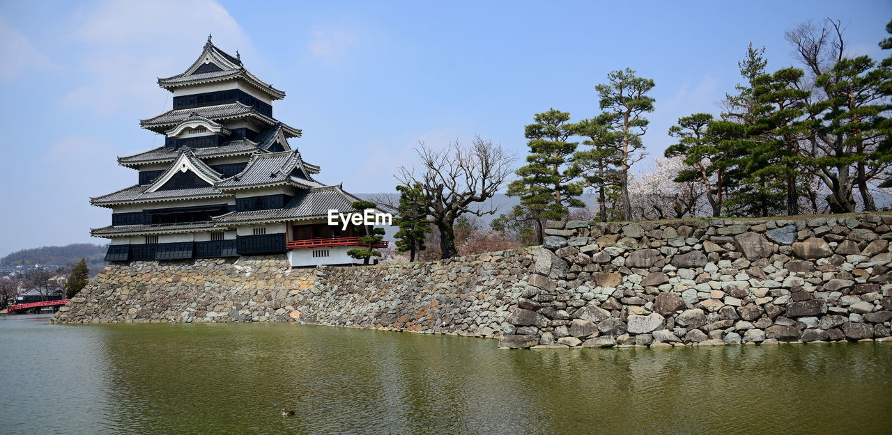 STONE WALL BY LAKE AGAINST BUILDINGS