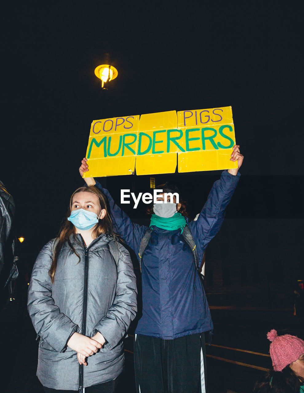 PEOPLE STANDING AGAINST ILLUMINATED SIGN