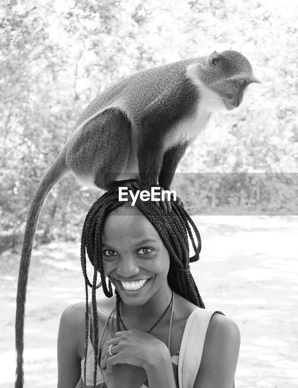 Portrait of happy woman with monkey standing outdoors