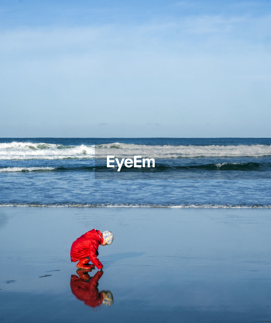 MAN WITH RED UMBRELLA ON BEACH AGAINST SKY