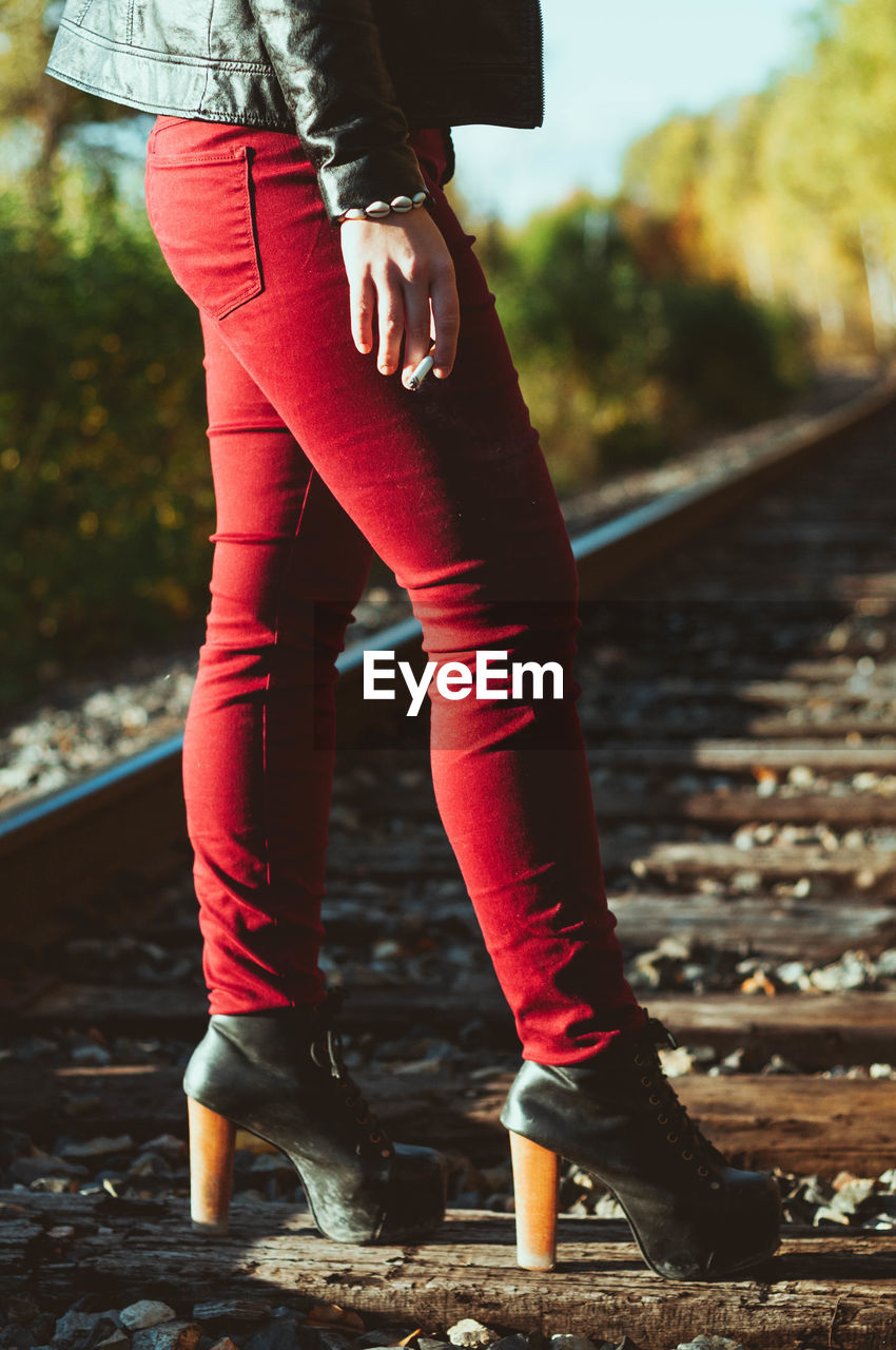 Low section of woman standing on railroad tie