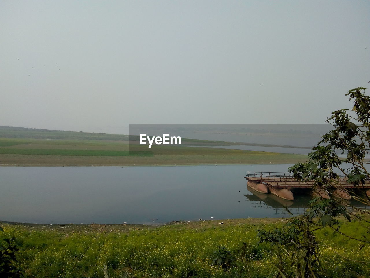 SCENIC VIEW OF LAKE BY FIELD AGAINST SKY