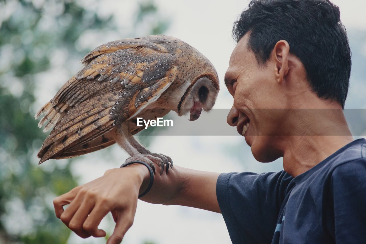 Smiling man holding owl on hand
