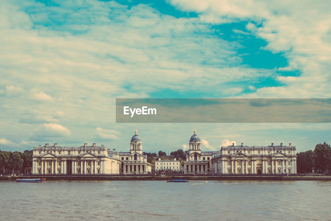 Royal navy college by thames river against sky