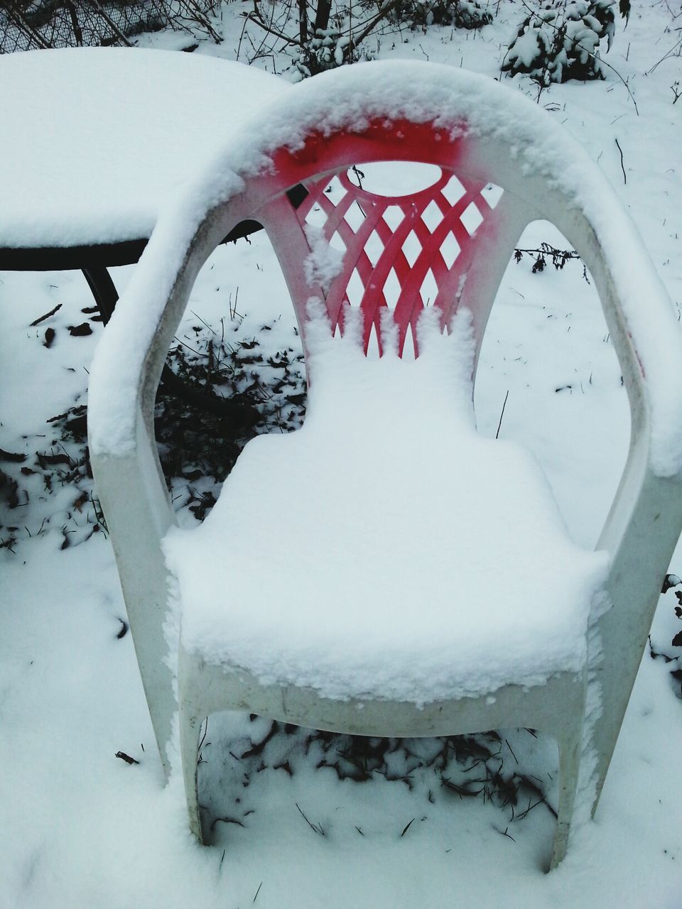 Snow covered chair and table on field