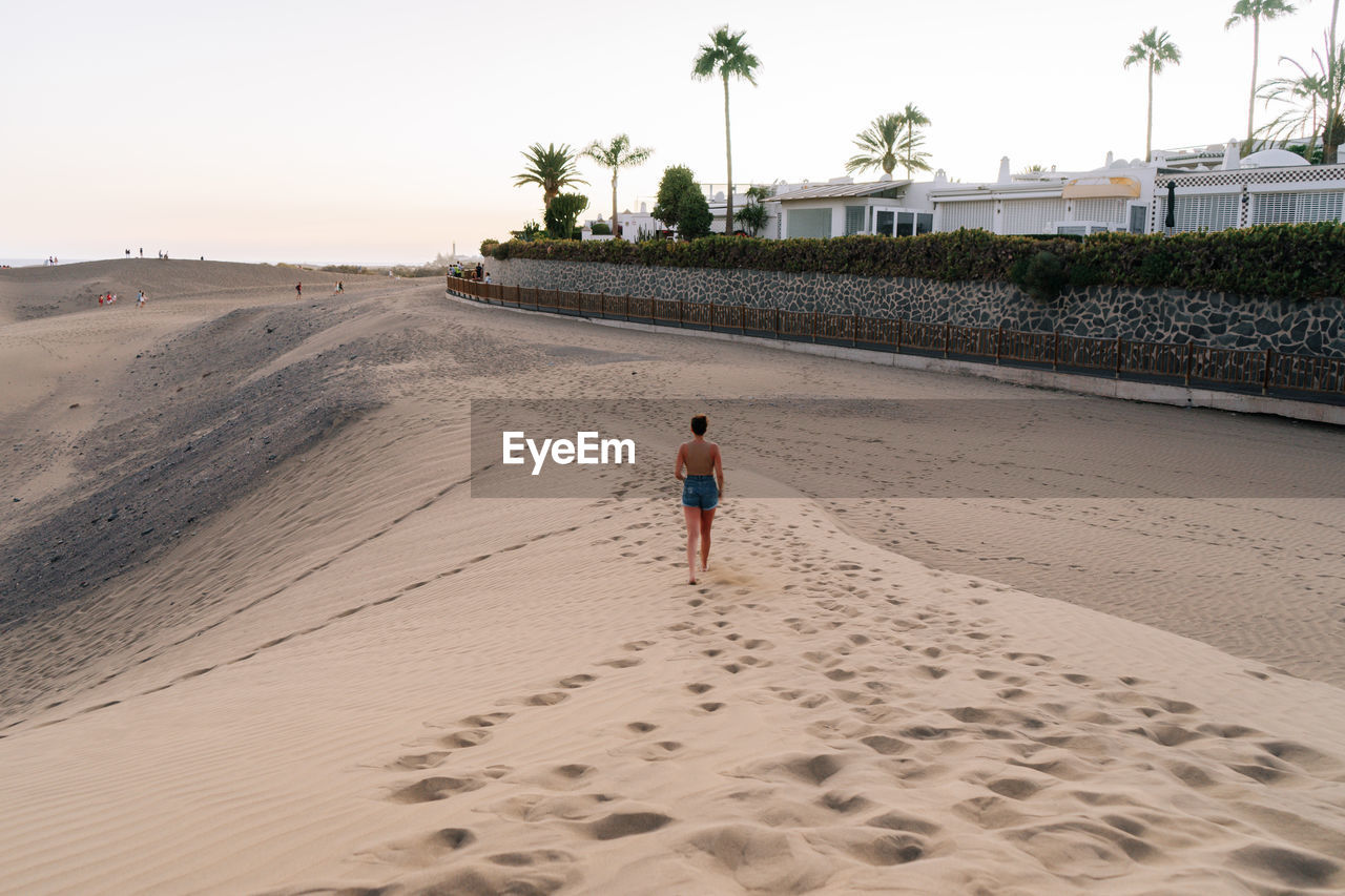 rear view of woman walking on sand at beach