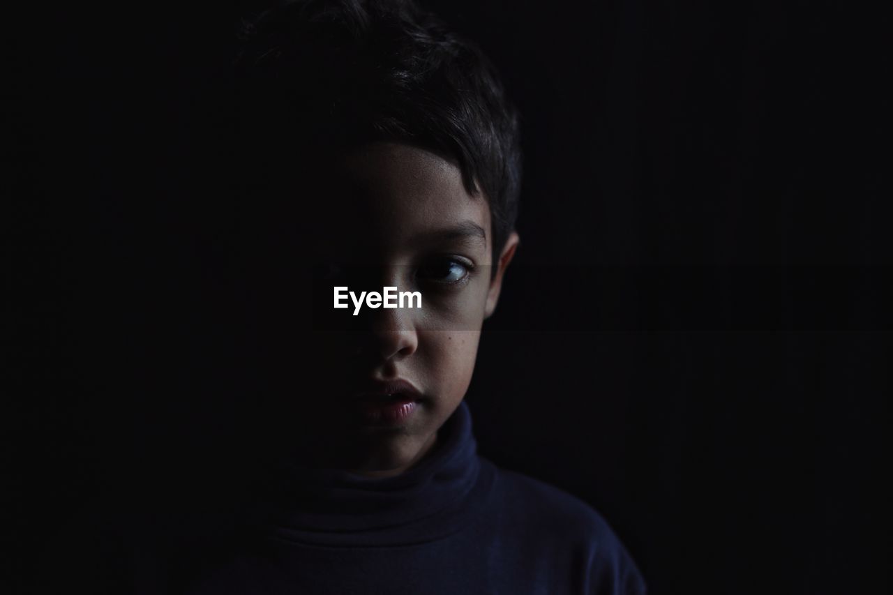 Portrait of boy over black background