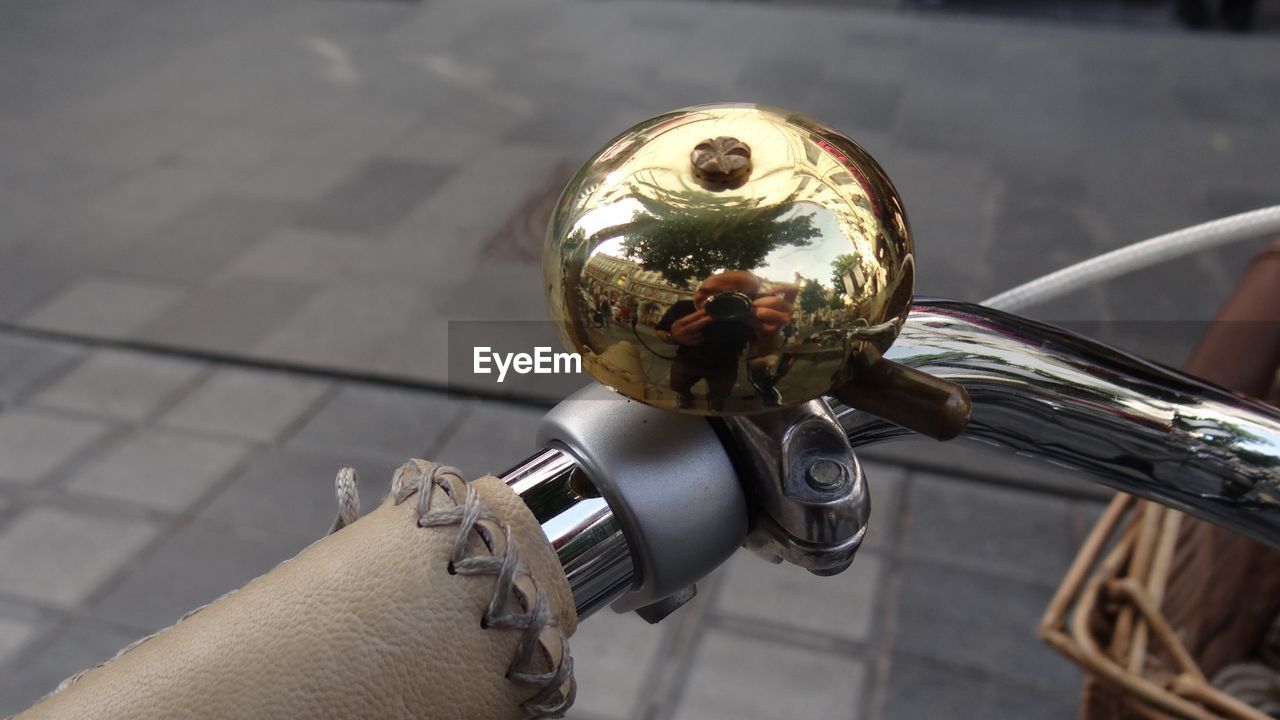 Reflection of man photographing on bicycle bell