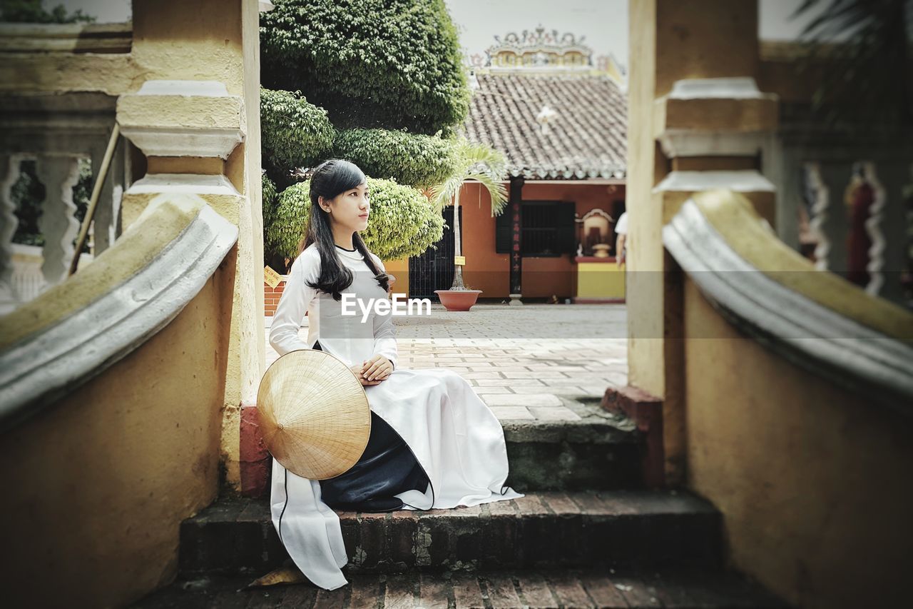 Woman sitting on staircase outside building