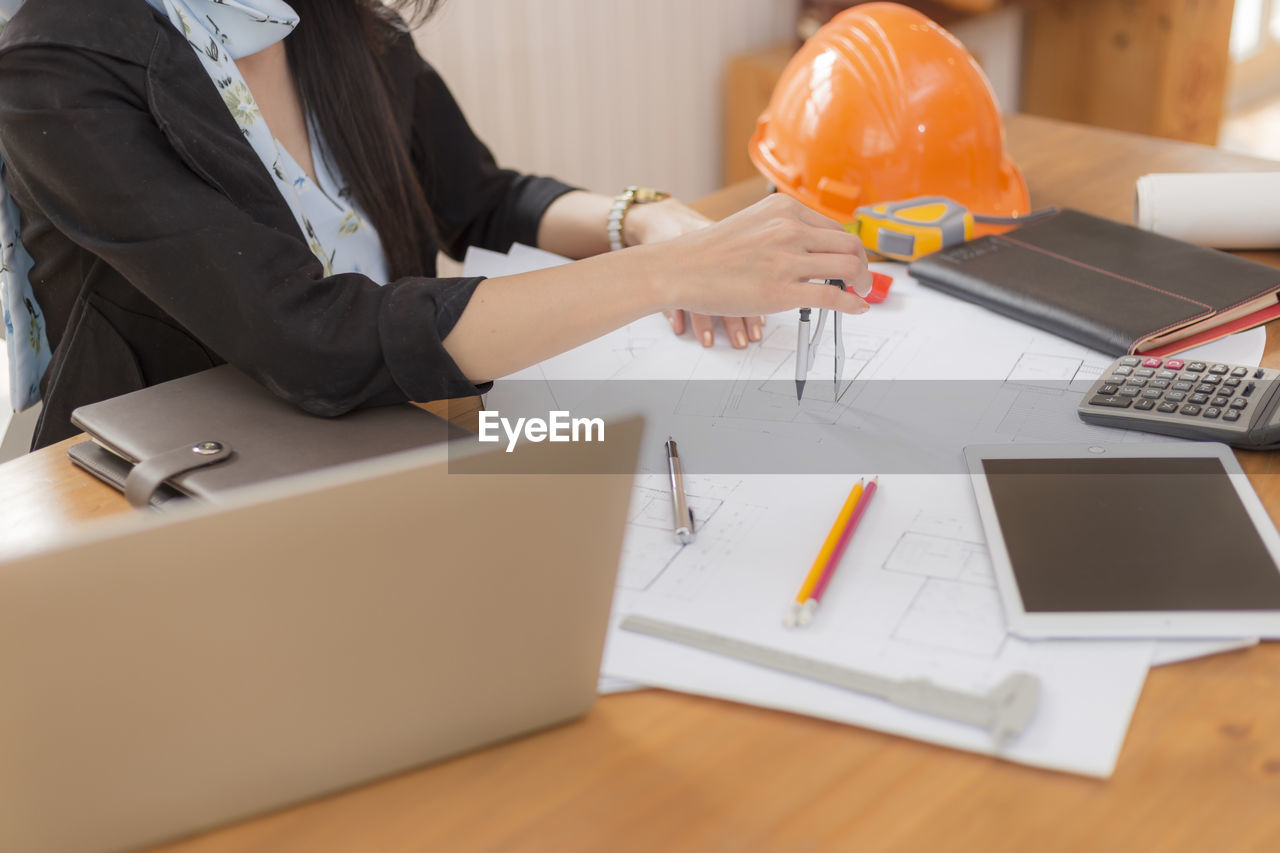 LOW ANGLE VIEW OF WOMAN WORKING AT TABLE