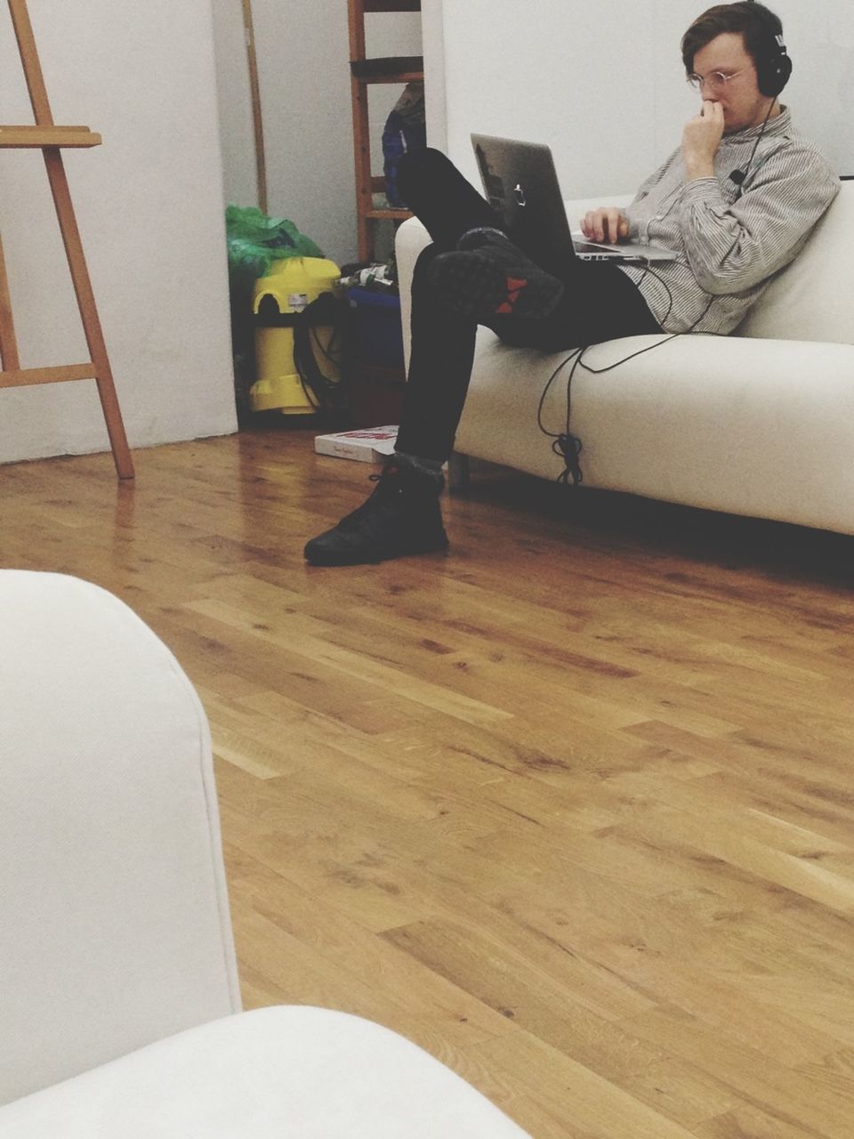 Full length of man using laptop while sitting on couch at office