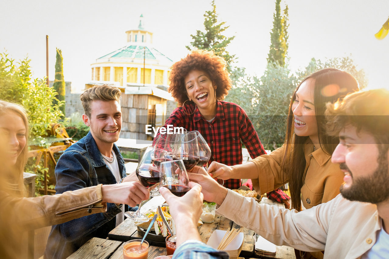 Smiling friends toasting drinks on table