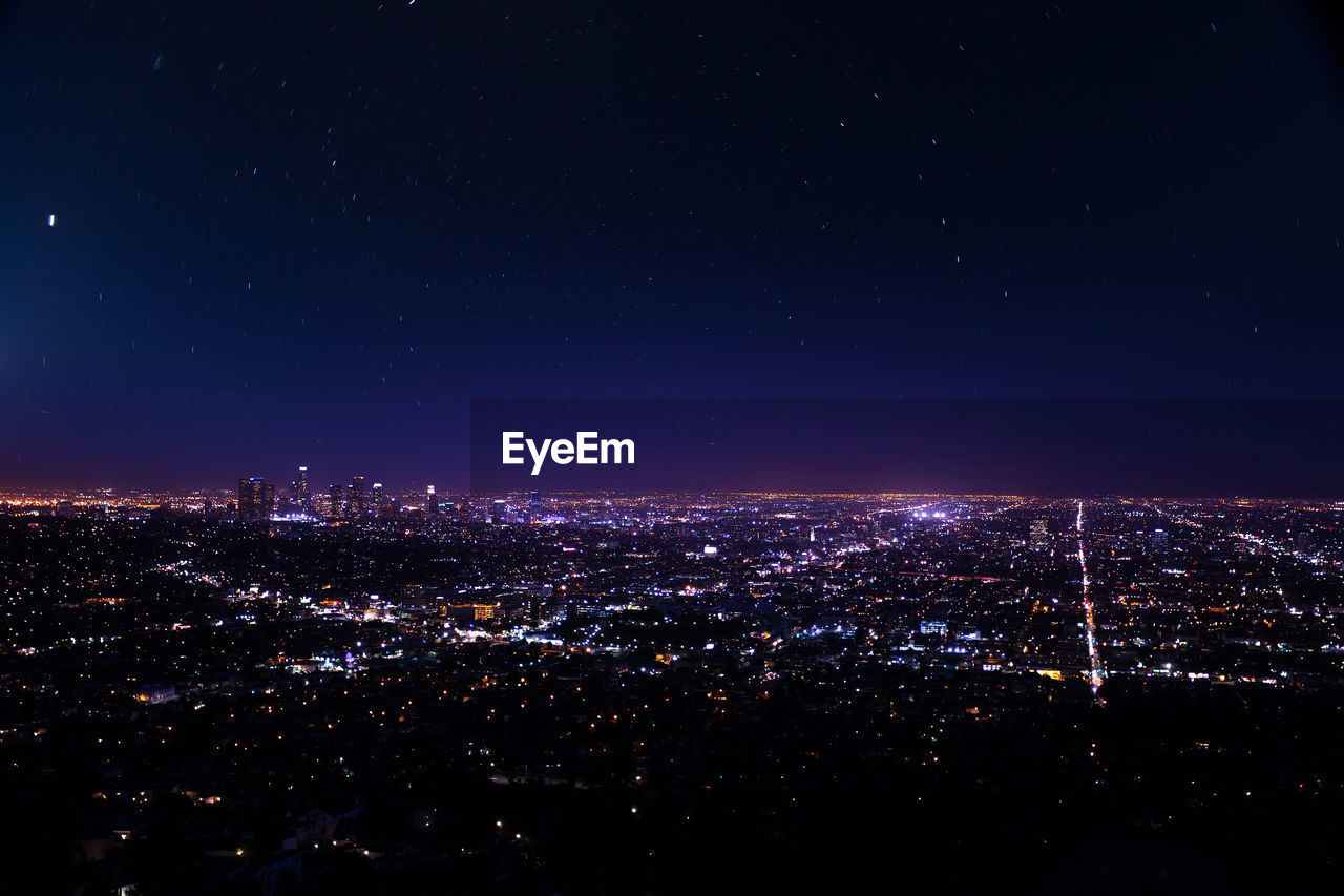 HIGH ANGLE VIEW OF ILLUMINATED CITY BUILDINGS AT NIGHT