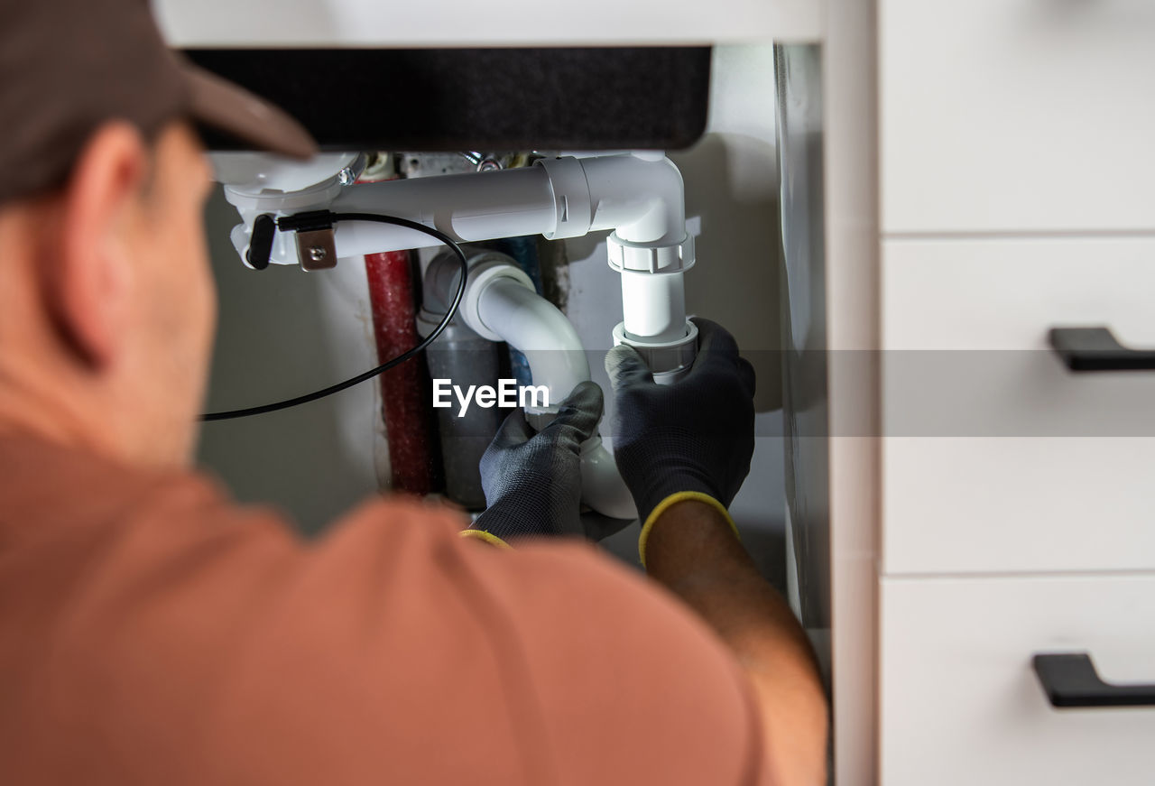 Plumber repairing pipe at home