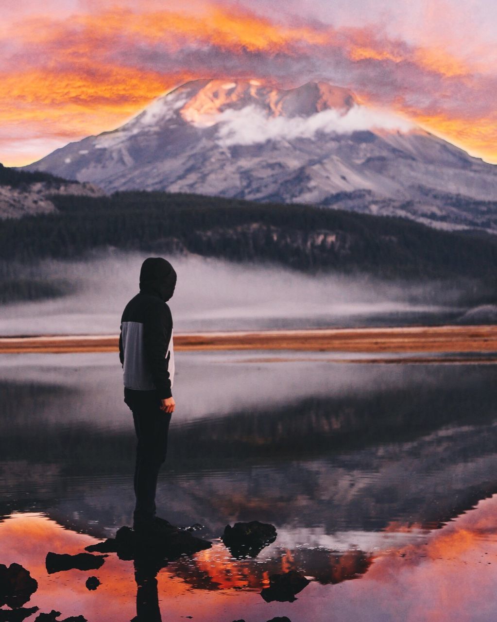 Man standing on rock in sparks lake against mountain during sunset