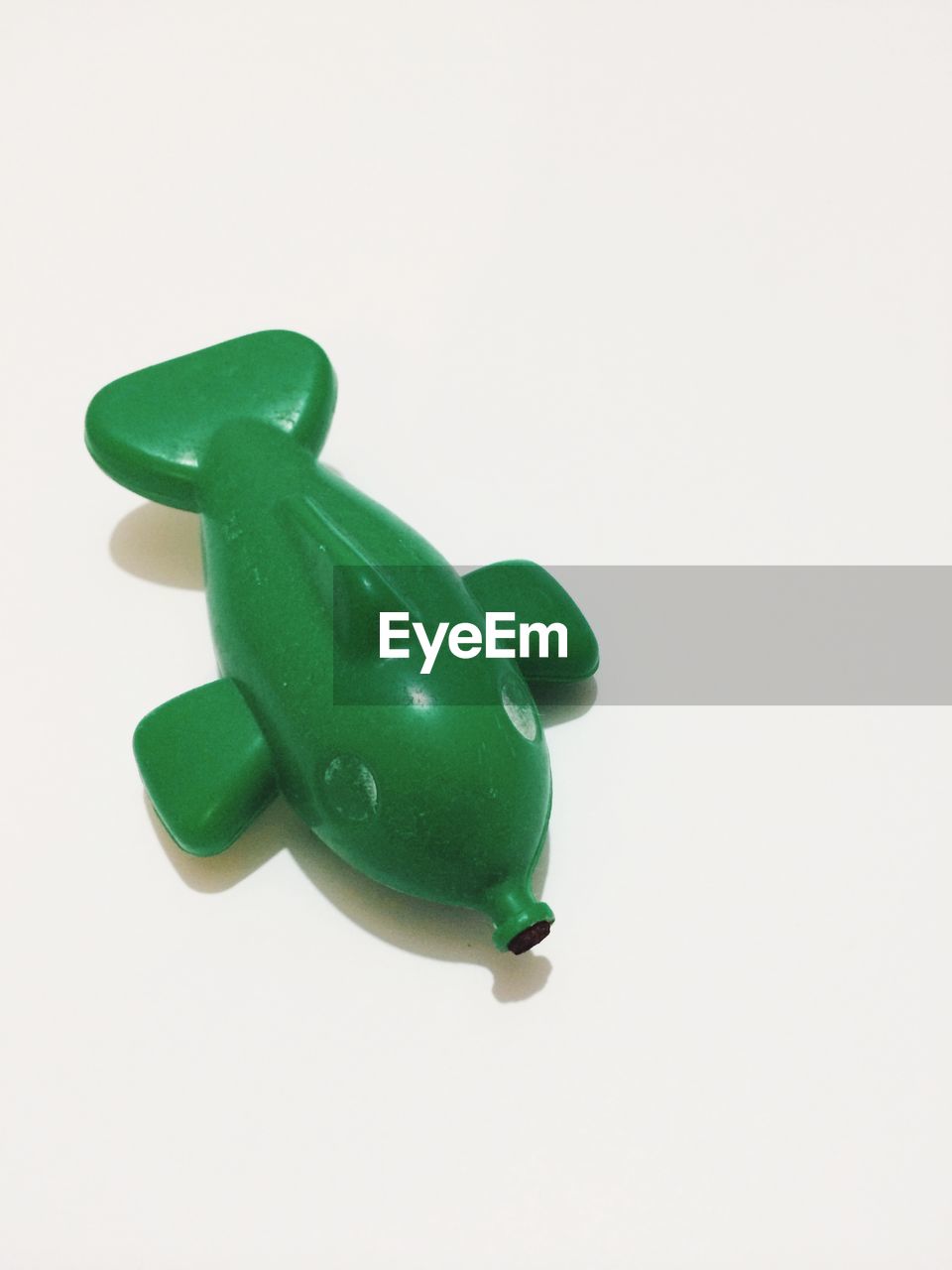 High angle view of green toy fish against white background