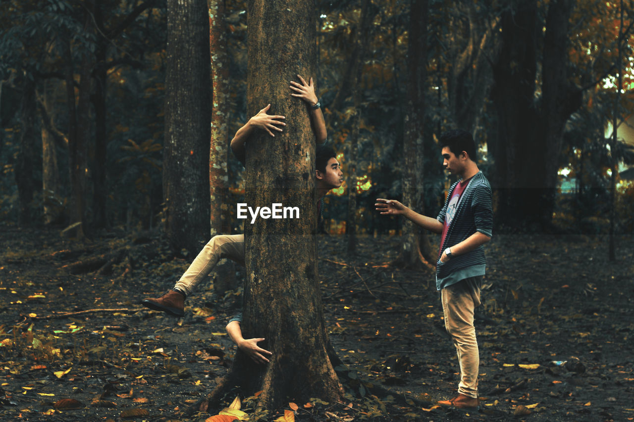 Digital composite of man gesturing towards himself embracing tree