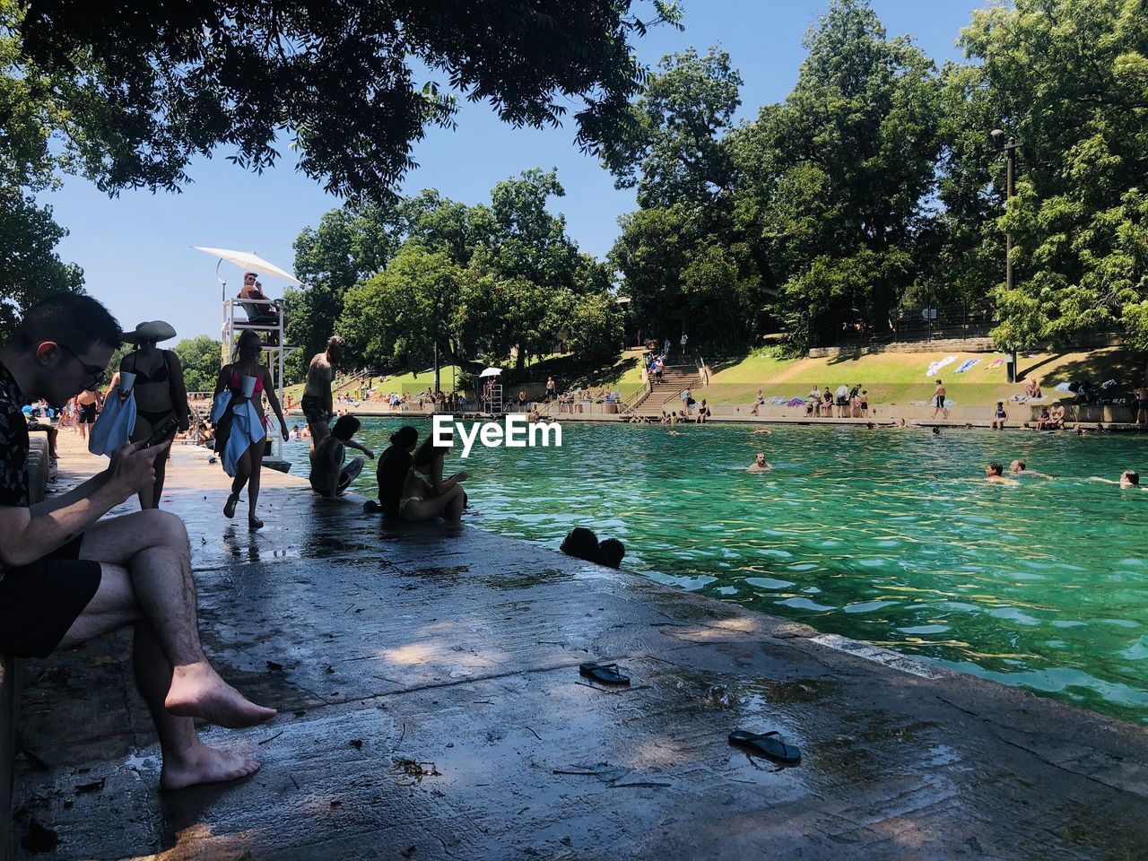 PEOPLE IN SWIMMING POOL BY LAKE