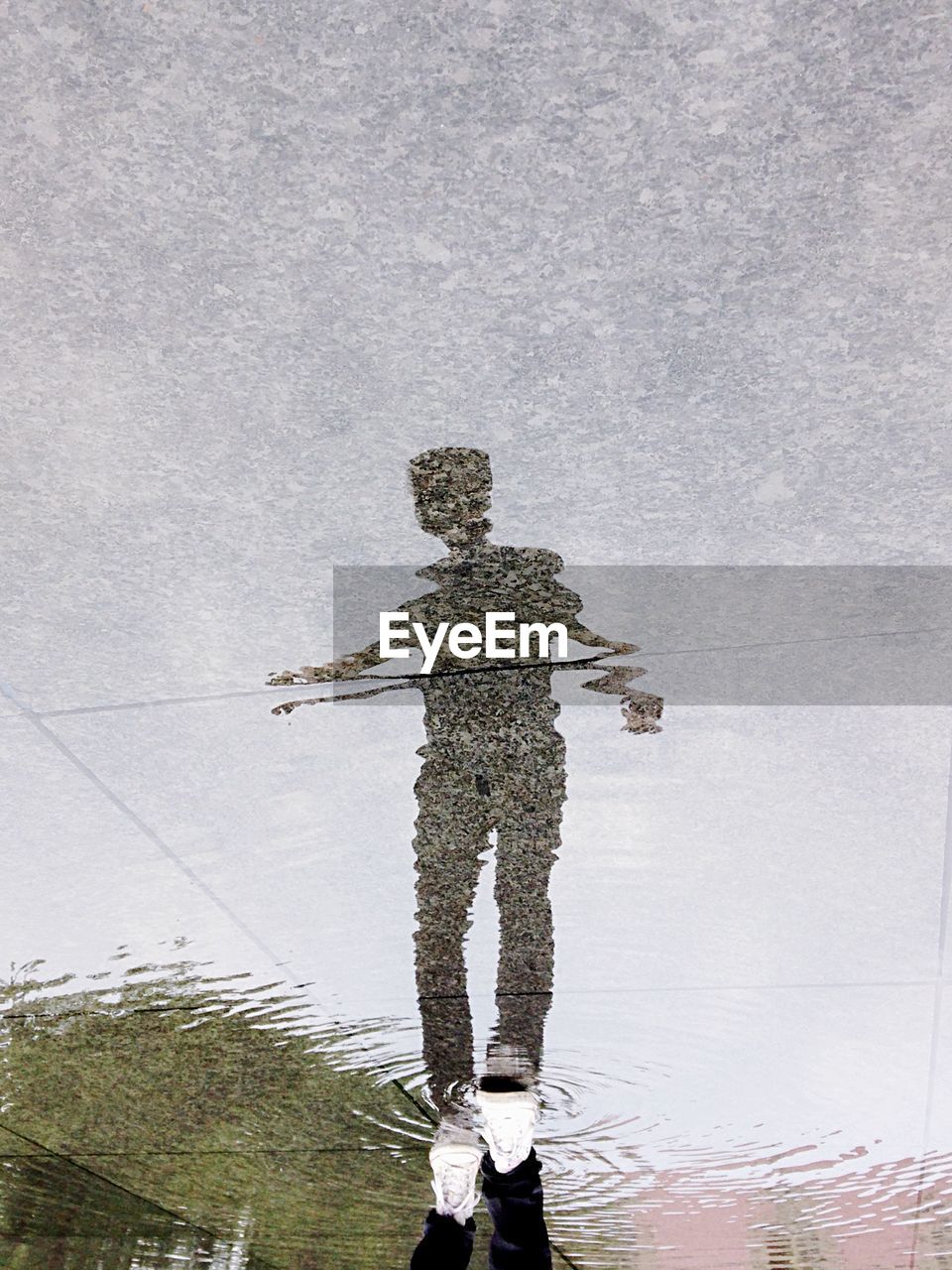 Reflection of man walking on puddle