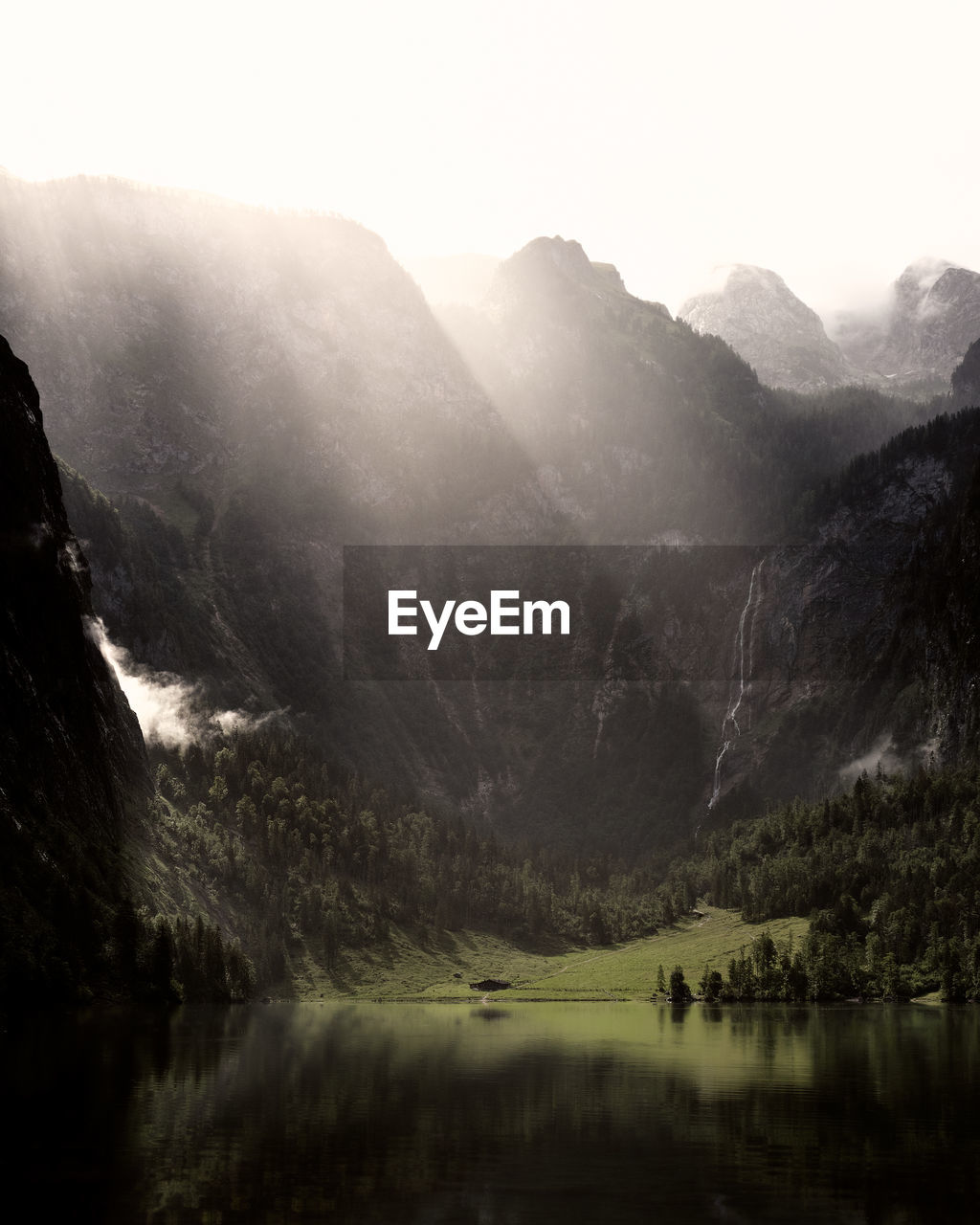 Scenic view of lake against mountains in foggy weather