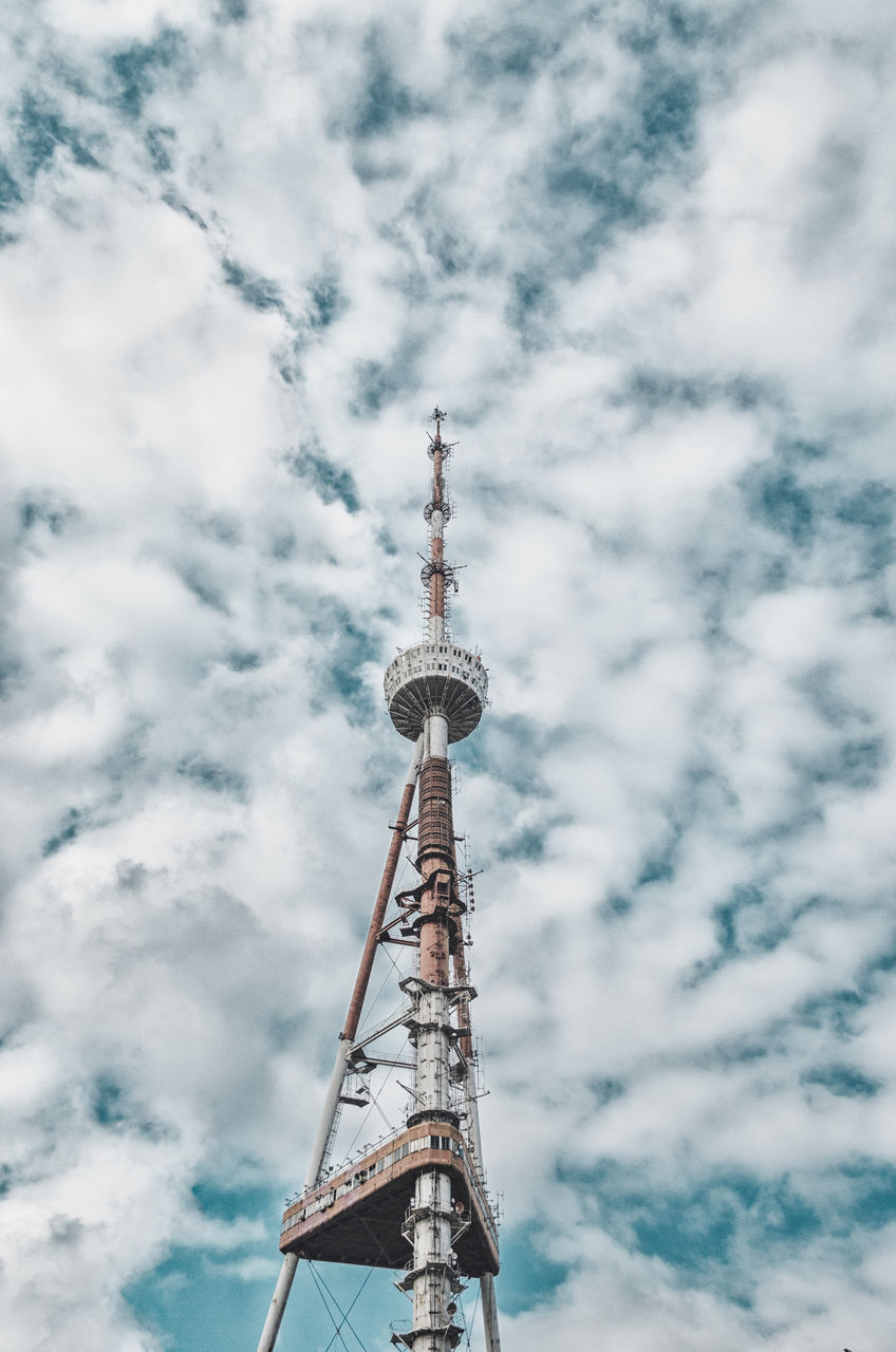 Low angle view of communications tower against cloudy sky