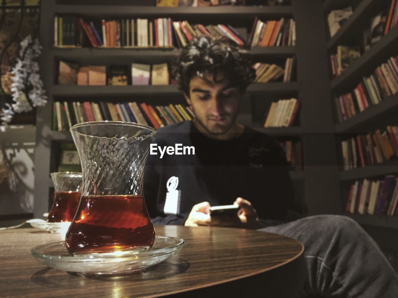 YOUNG MAN USING SMART PHONE WHILE SITTING IN RESTAURANT