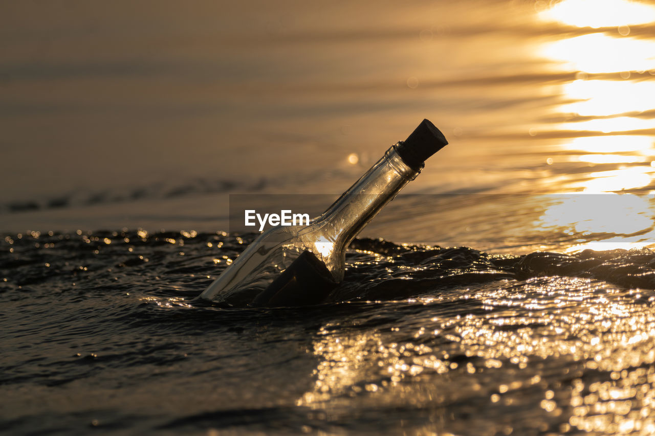 Message in a bottle in gently moving water at sunset