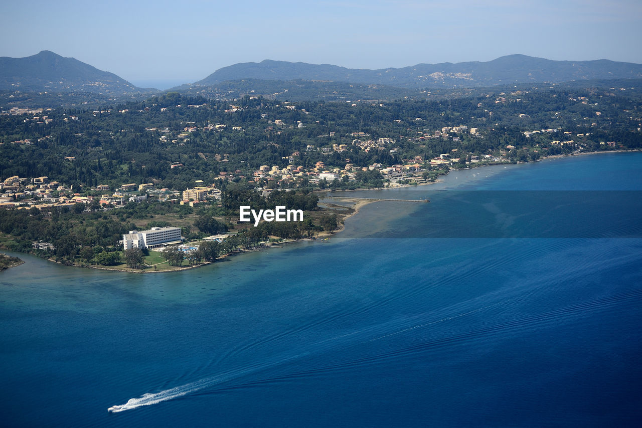 Aerial view of city by sea against sky