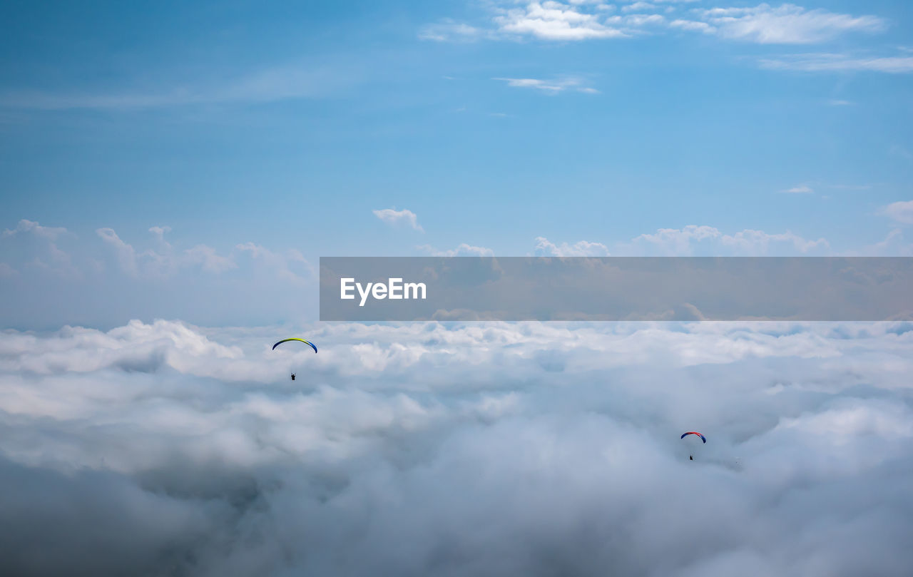 People paragliding against cloudy sky