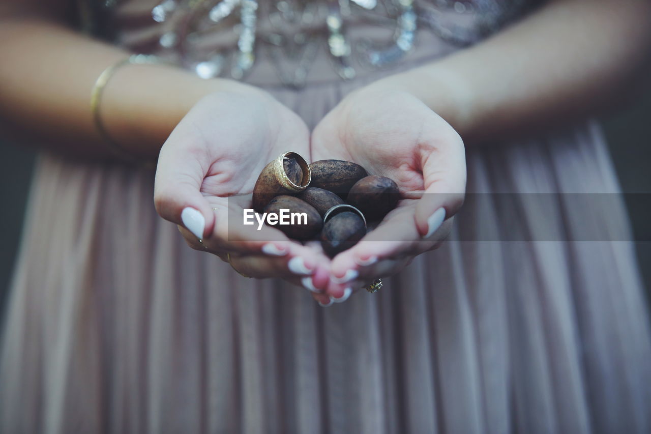 Midsection of bride holding wedding rings and seeds