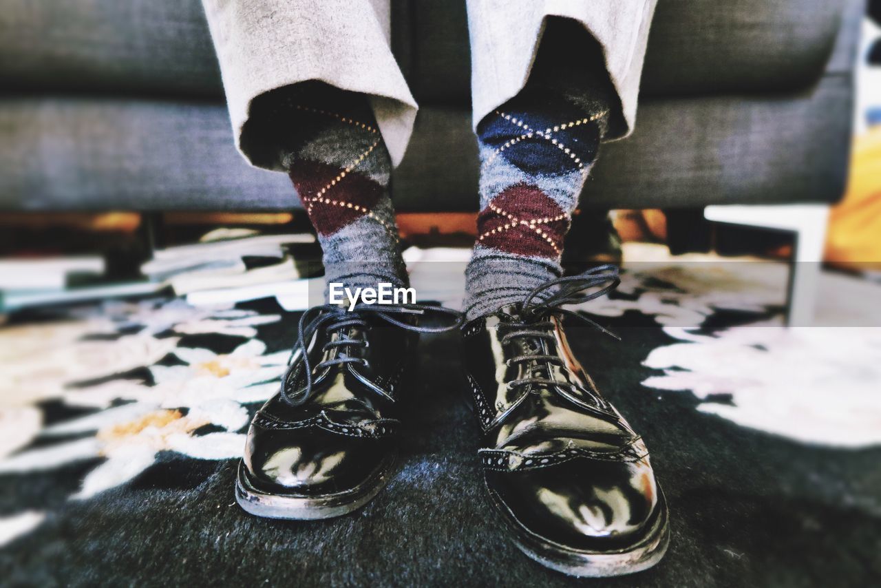 Low section of man wearing dress shoe on rug