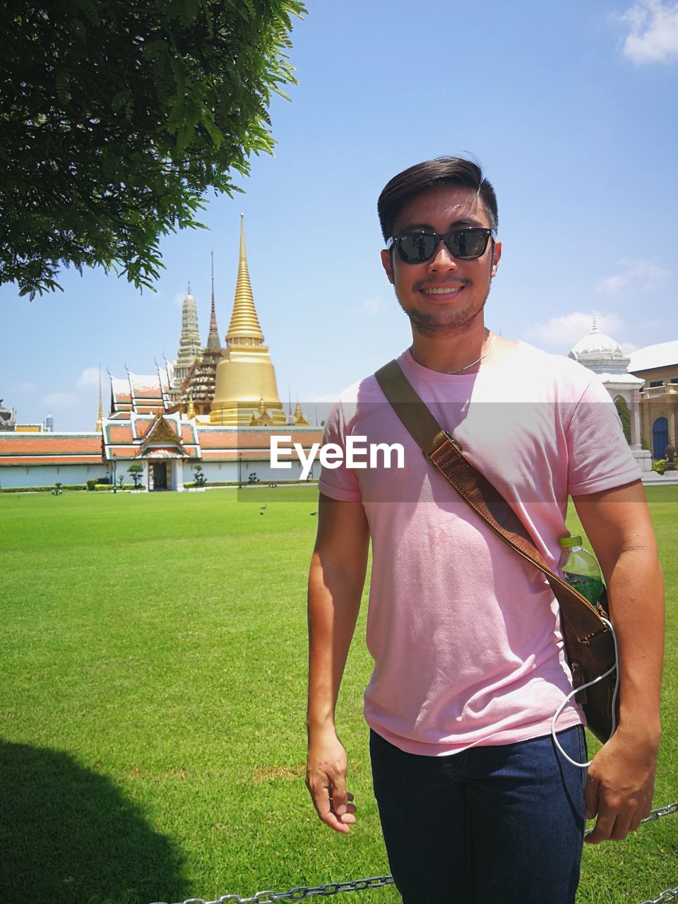 Portrait of young man wearing sunglasses while standing against pagoda