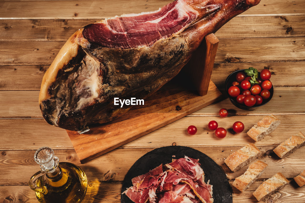 Close-up shot of a spanish iberian ham with tomato, olive oil and bread on a wooden table