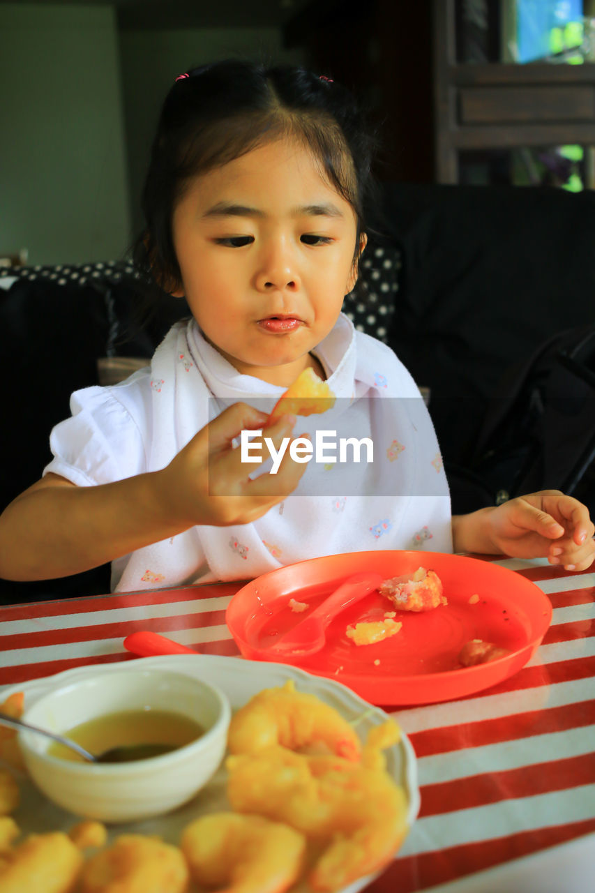 Cute girl eating food at home