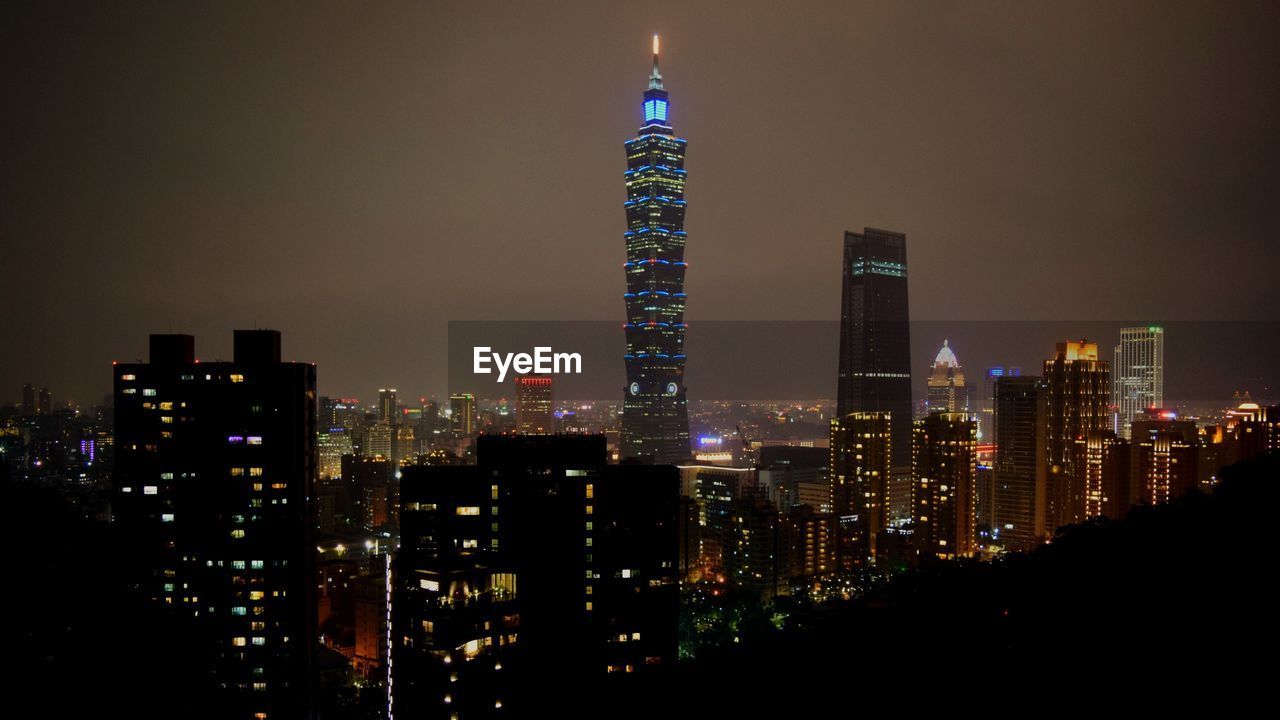 ILLUMINATED MODERN BUILDINGS AGAINST SKY AT NIGHT