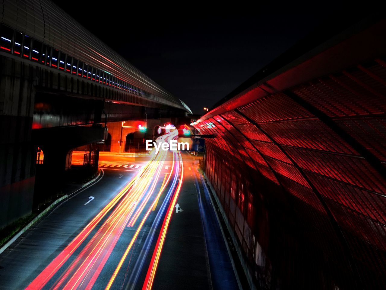 LIGHT TRAILS ON ROAD IN ILLUMINATED CITY