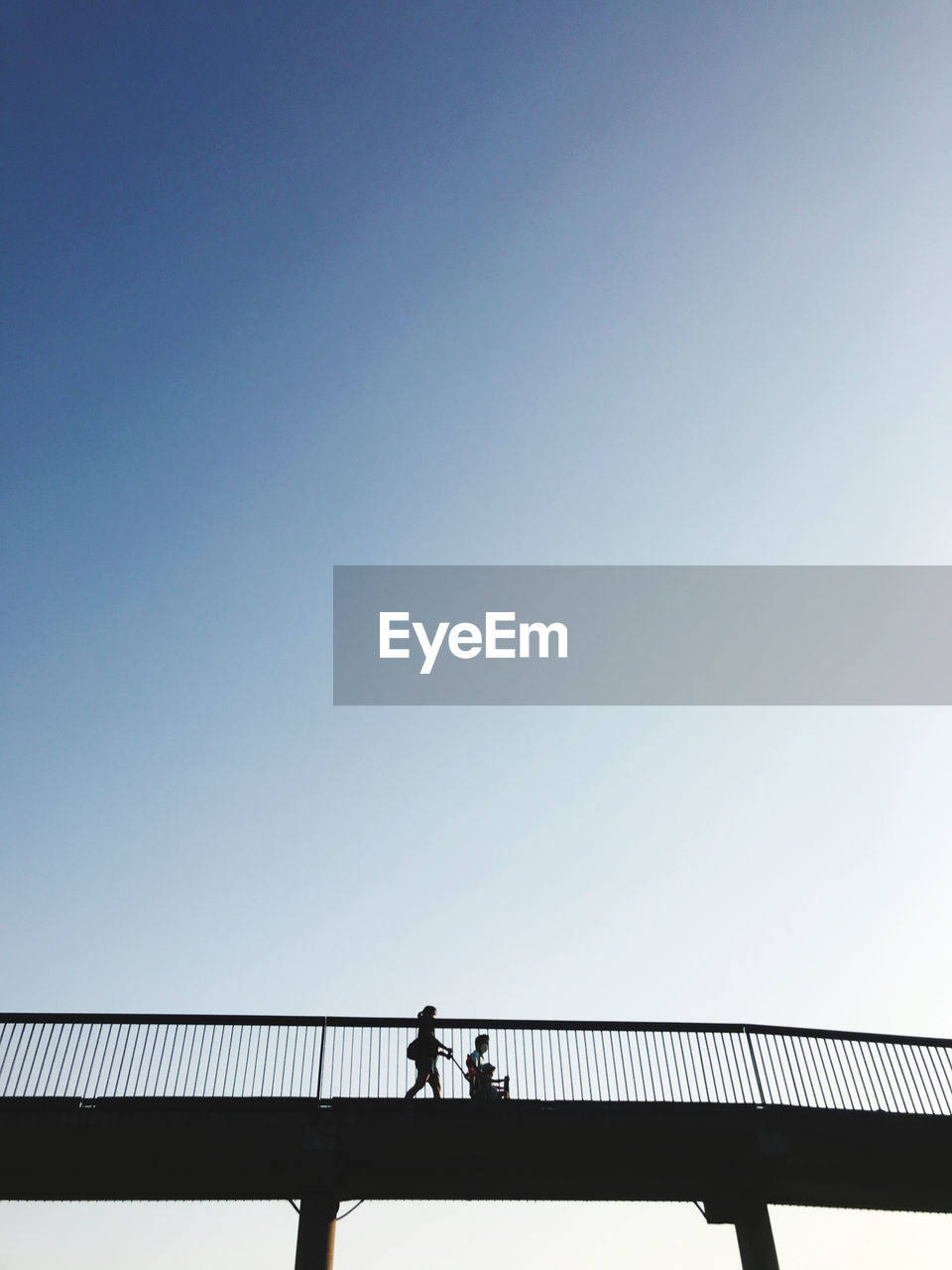 sky, bridge, railing, copy space, architecture, clear sky, silhouette, one person, built structure, nature, men, adult, line, day, blue, walking, full length, low angle view, lifestyles, horizon, outdoors, transportation, standing, women, travel, cloud, sunlight, leisure activity