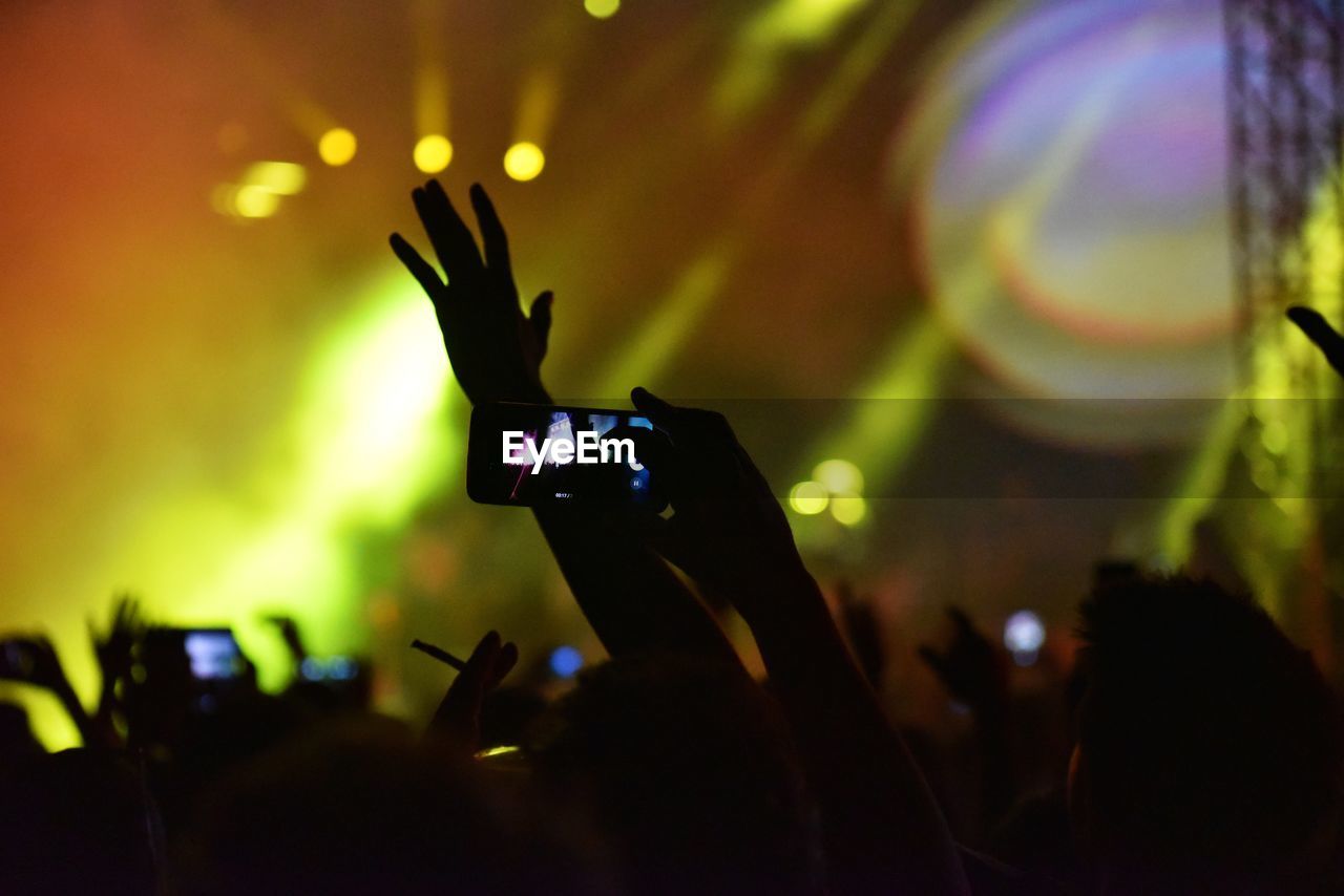 Silhouette of person holding mobile phone at concert