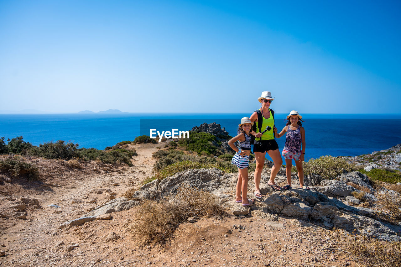 sky, sea, adult, water, nature, land, coast, full length, beach, leisure activity, blue, two people, men, activity, copy space, travel, women, holiday, clear sky, trip, vacation, sports, togetherness, day, scenics - nature, adventure, lifestyles, horizon over water, horizon, beauty in nature, ocean, young adult, mountain, rock, friendship, outdoors, landscape, travel destinations, sunlight, clothing, hiking, sunny, environment, female, terrain, walking, shore, sports clothing, exercising, relaxation, person, motion, mountain bike, cliff, happiness, emotion, mature adult, backpack